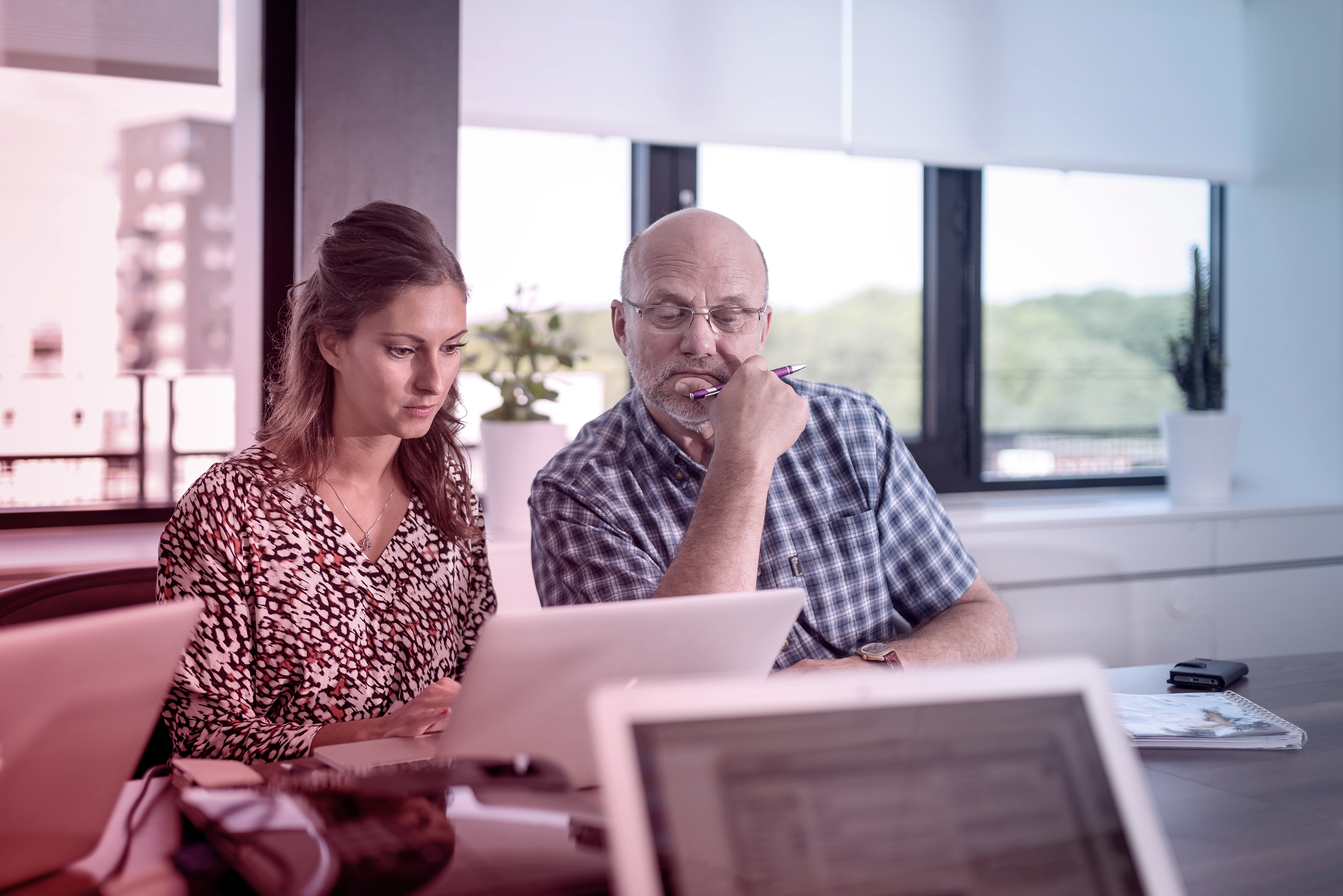 Två kollegor i HR-samtal över en laptop i ett modernt svenskt kontor med naturligt ljus